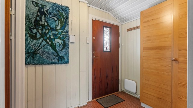 Overbygget inngangsparti med entrédør utstyrt med sikkerhetslås.