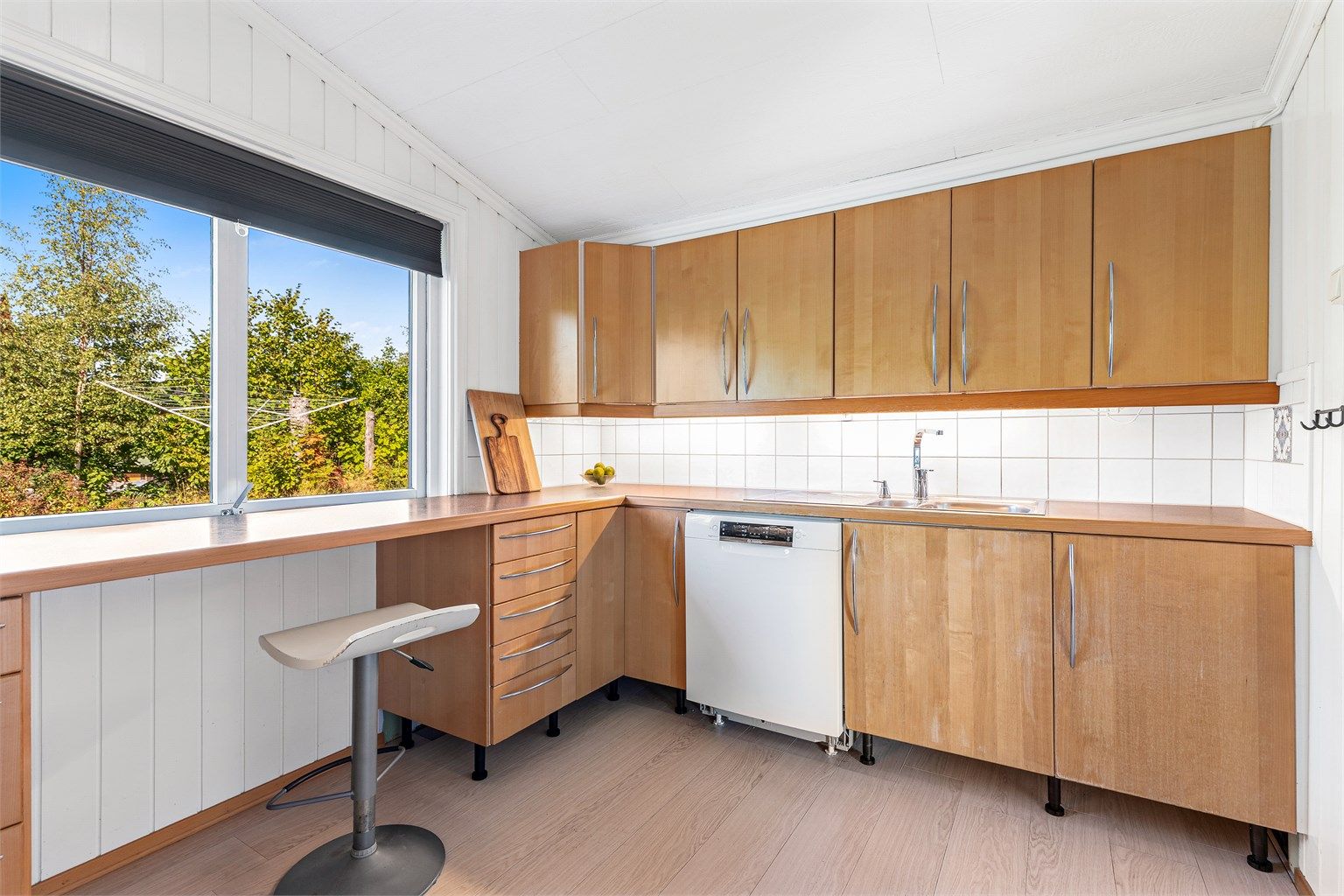 IKEA kjøkkenløsning fra ukjent årstall med innredning i glatte fronter og laminert benkeplate. Flislagt vegg mellom benkeplate og overskap, med belysning under overskap og stikkontakter. 