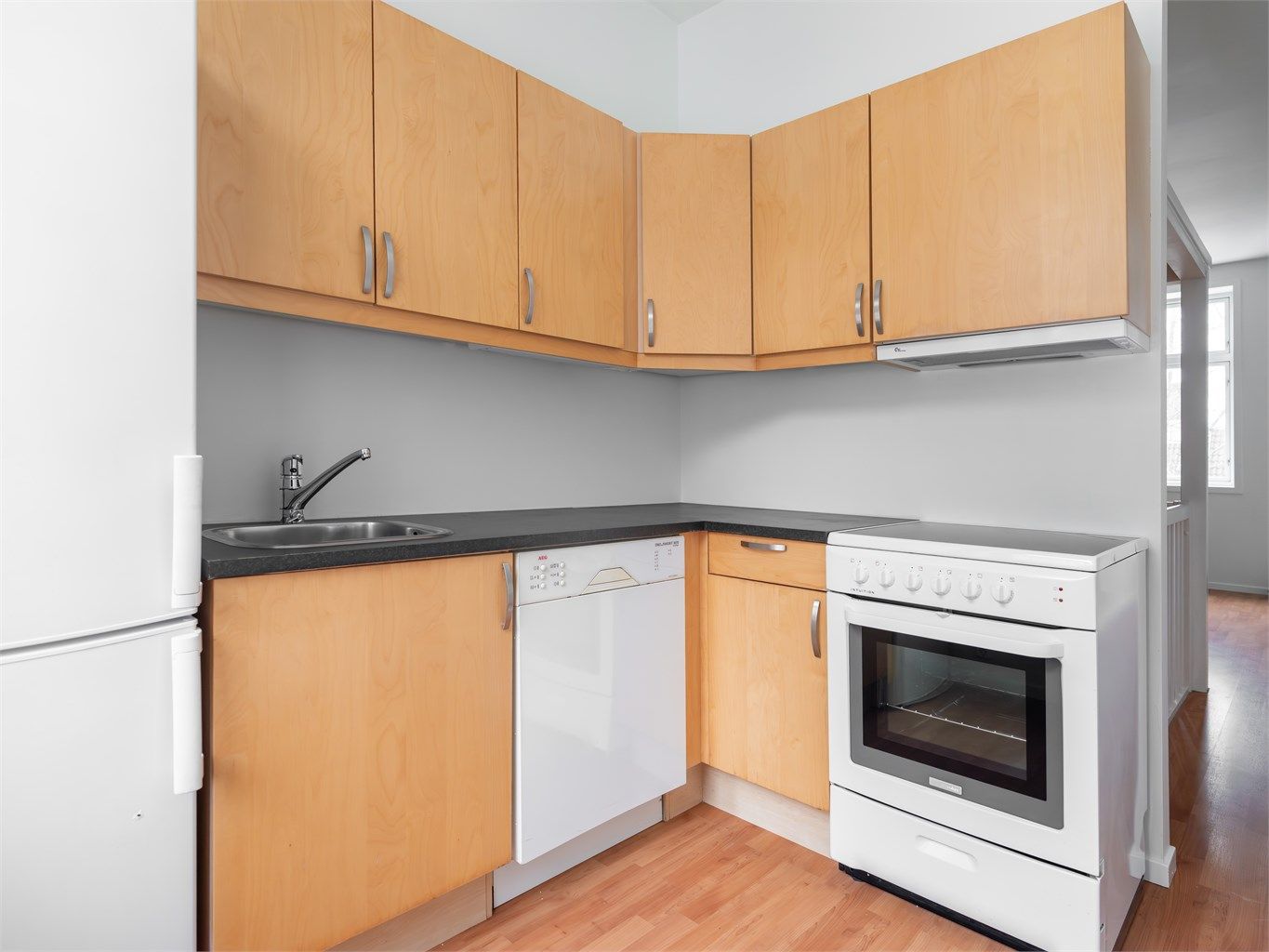 Kjøkkenet ligger tilbaketrukket fra stuen og er innredet med komfyr, oppvaskmaskin og kjøleskap med fryser. Vegger malt senere tid.