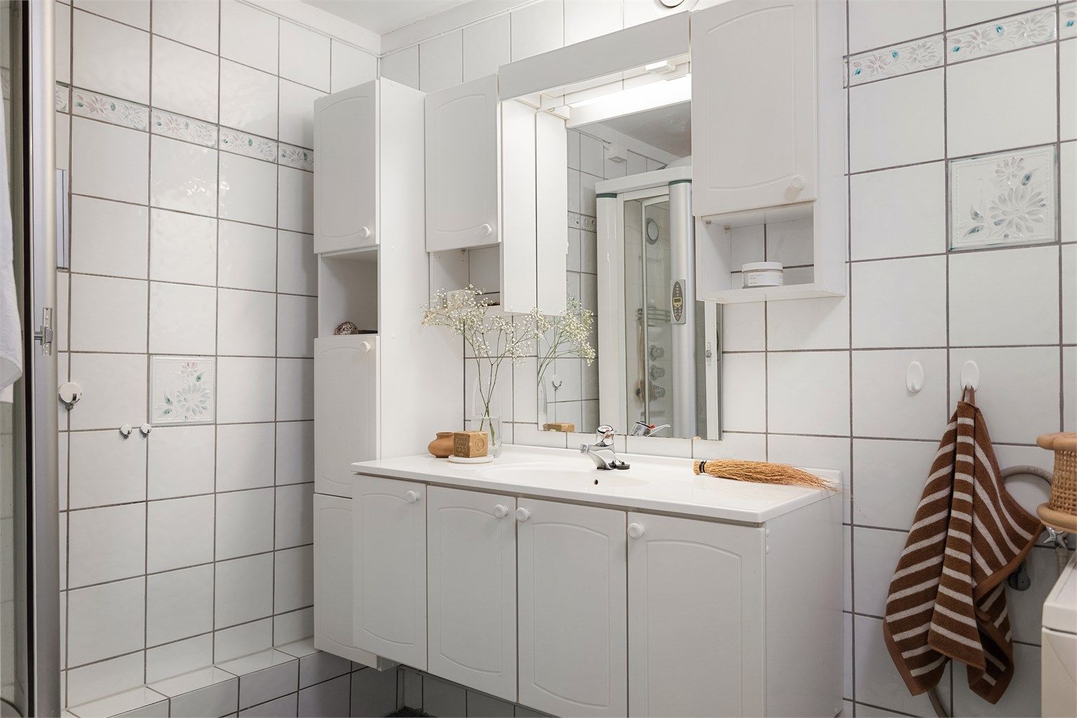 Servantinnredning med skap, høyskap og speil over sørger for gode oppbevaringsmuligheter på badet.