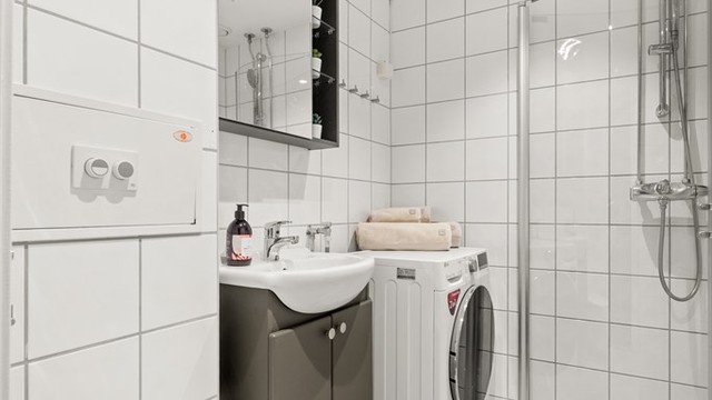 Tidløst, flislagt bad med varmekabler i gulvet og opplegg for vaskemaskin.