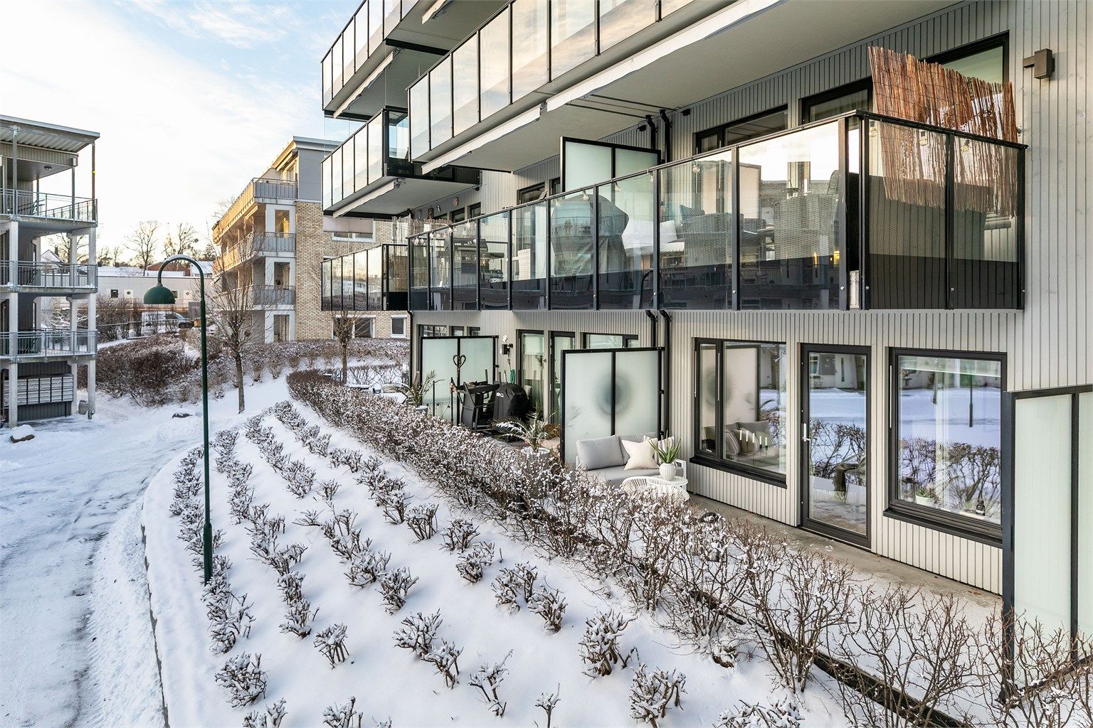 Ute på den romslige plattingen kan du sommerstid sitte henvendt mot solens gang dagen gjennom. Prydbuskene foran fylles av blader som skaper naturlig skjerming.