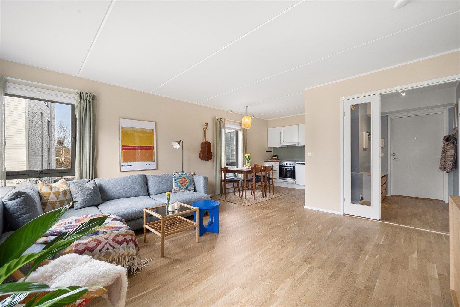 Den delvis åpne løsningen mellom stue og kjøkken skaper en sosial og luftig sone, perfekt for samvær med familie og venner.