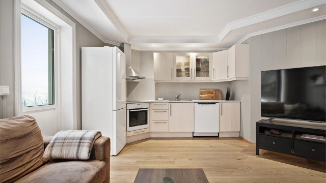 Kjøkkeninnredning med over- og underskap samt vitrineskap i lys og glatt utførelse