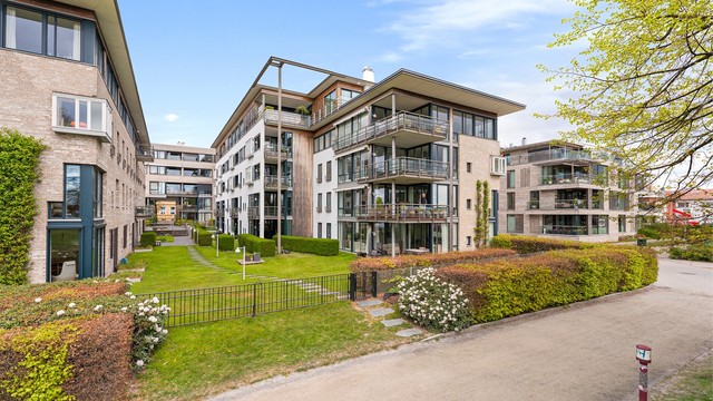 Leiligheten ligger tilbaketrukket nest innerst på høyre side i bygget til høyre med utsikt mot oss