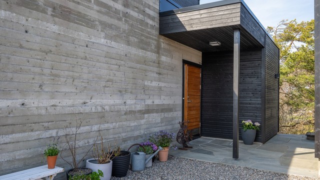 Inngangspartiet er innbydende og kombinerer liggende trekledning med en støpt platting belagt med naturskifer.