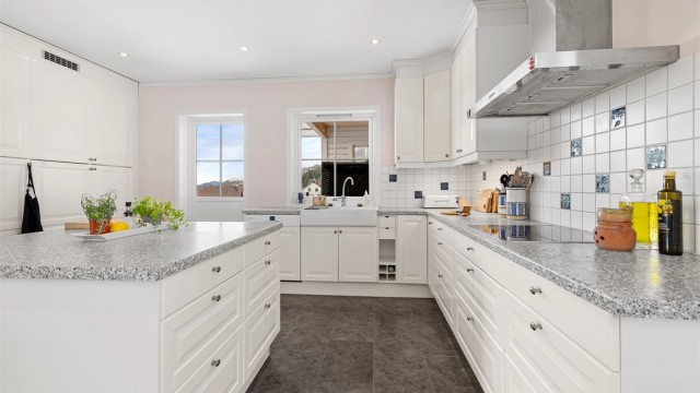 En stor kjøkkenøy gir ekstra arbeidsflate og fungerer som et sosialt midtpunkt i rommet.