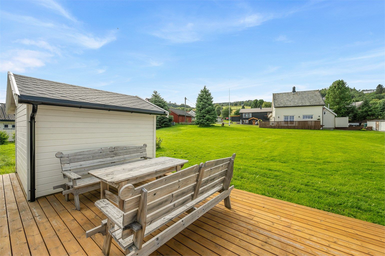 Ved garasjeområdet er det etablert en hyggelig terrasse med sittegruppe og utsyn over de store grøntarealene.