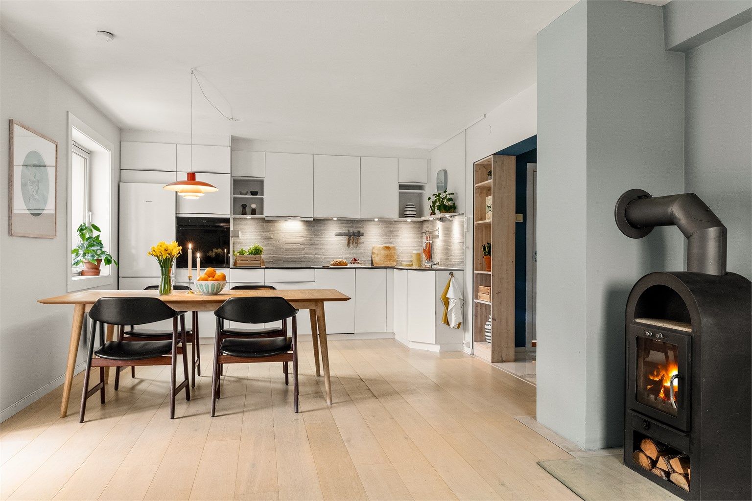 Leiligheten har en åpen og sosial løsning mellom kjøkken og stue, hvor vedovnen skaper ekstra hygge. Foto: Fotostallen v/ Lars-Petter Skillestad