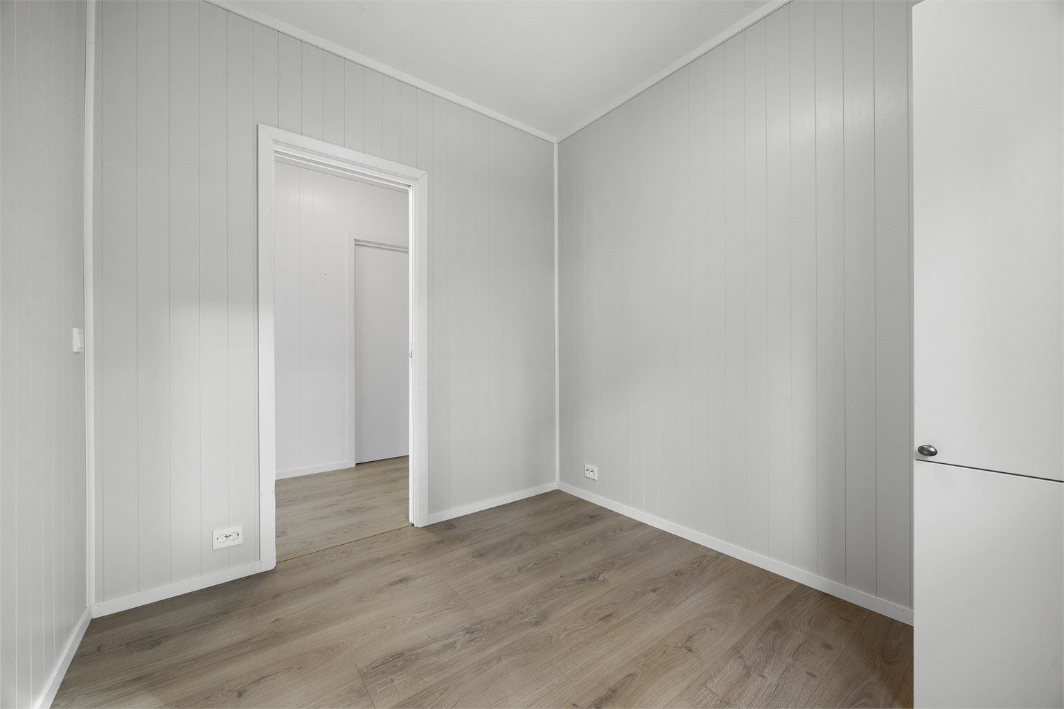 Soverommet har laminatgulv og panelte overflater.