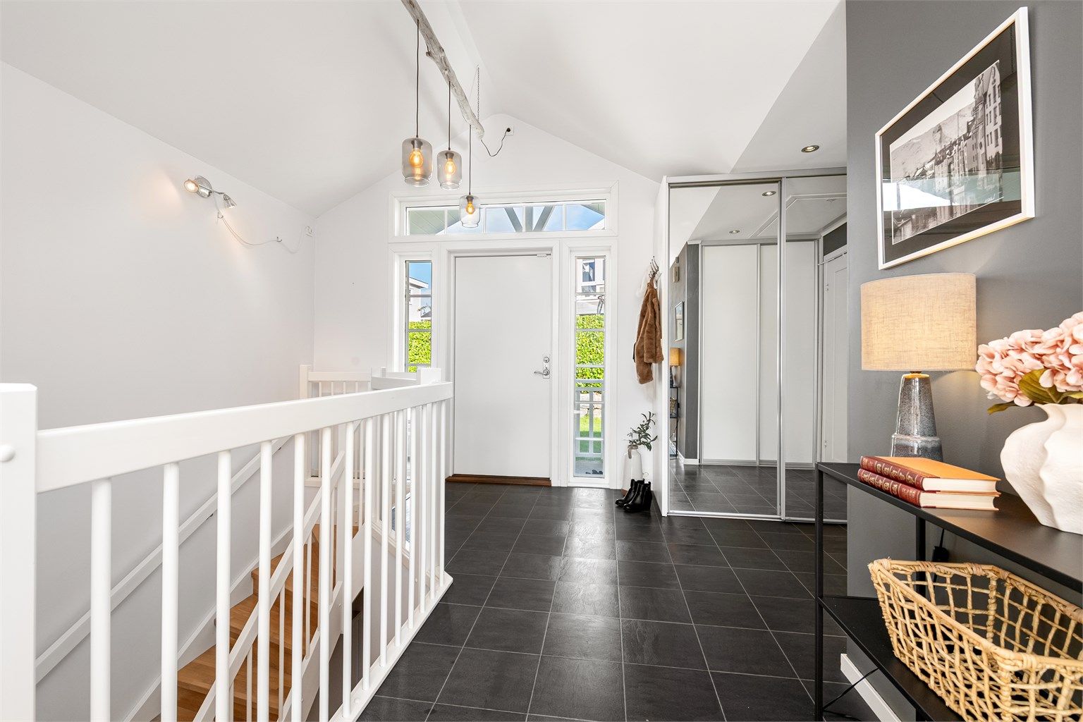 Entré med flislagt gulv, god takhøyde og skyvedørsgarderobe med speilfronter.