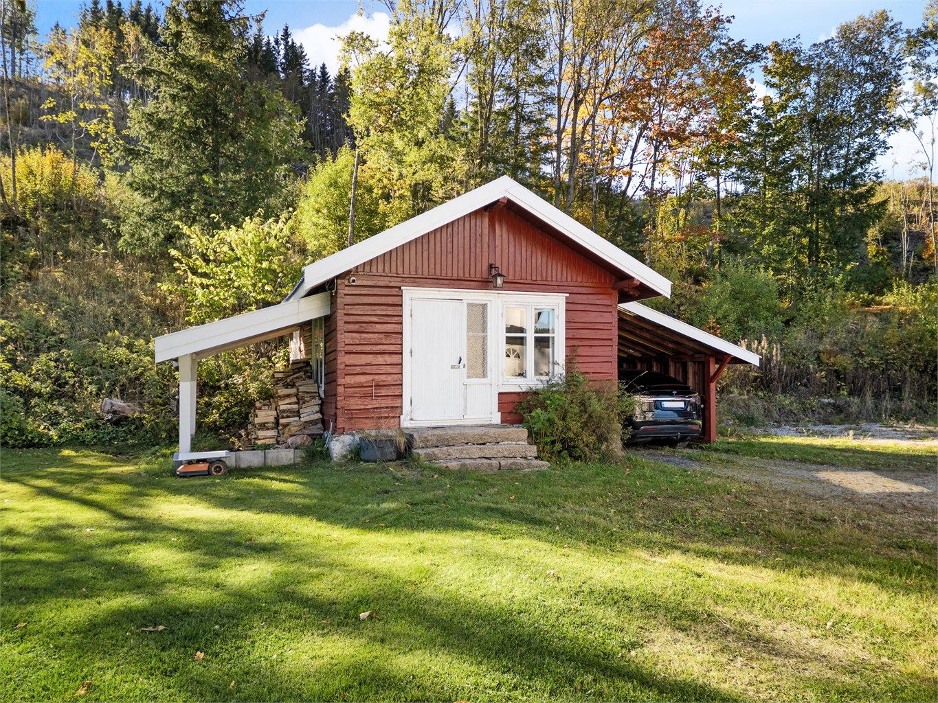 Frittstående bryggerhus i tømmer med tilstøtende carport (ikke byggemeldt) og takoverbygg for vedlagring (ikke byggemeldt).