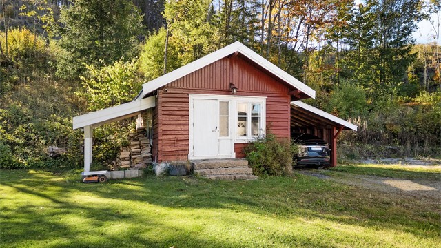 Frittstående bryggerhus i tømmer med tilstøtende carport (ikke byggemeldt) og takoverbygg for vedlagring (ikke byggemeldt).