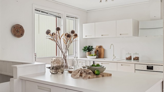 IKEA-kjøkken med hvite, slette fronter, laminatbenkeplate og integrerte hvitevarer.