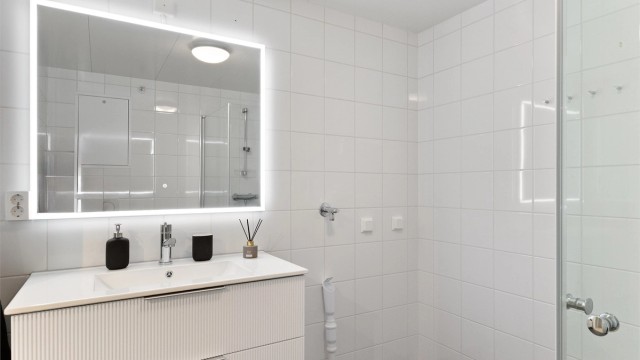 Baderomsinnredningen ble fornyet i 2026, med profilert servantskap og stort speil med integrert belysning som gir et lekkert og moderne preg. Praktisk opplegg for vaskemaskin gjør hverdagen enkel.