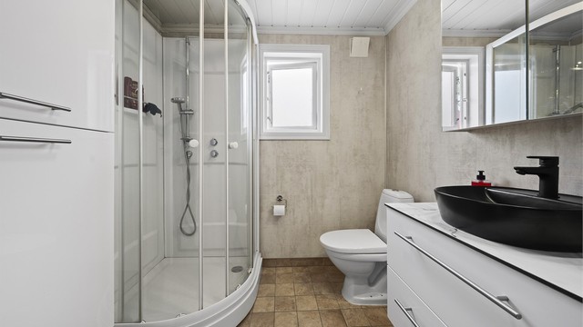 Badet i 1. etasje har flislagt gulv med varmekabler, baderomsplater på vegger og panel i himling.