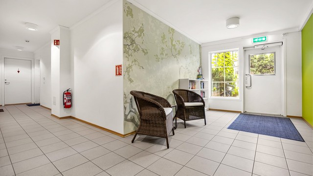 Felles inngangsparti med sittegruppe, bokhjørne og heis til etasjene.