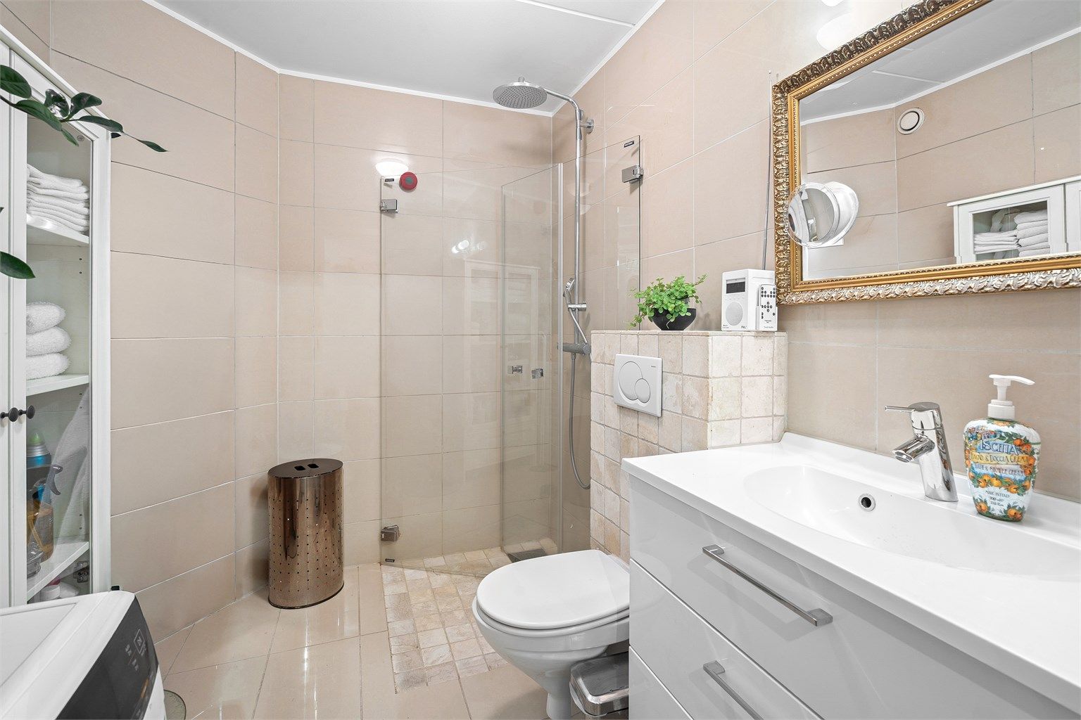 Flislagt bad med varmekabler i gulv. Rommet er utstyrt med vegghengt toalett tilkoblet innebygget sisterne og vegghengt servantskap med ovenpåliggende vask. Videre er det nedsenket dusjsone med innfellbare dusjdører og armatur tilkoblet hånd- og regndusj.