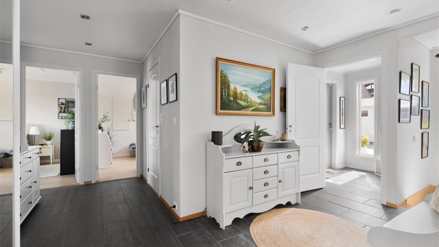 Videre inn til hall hvor det er fliser på gulv og skyvedørsgarderobe til oppbevaring.