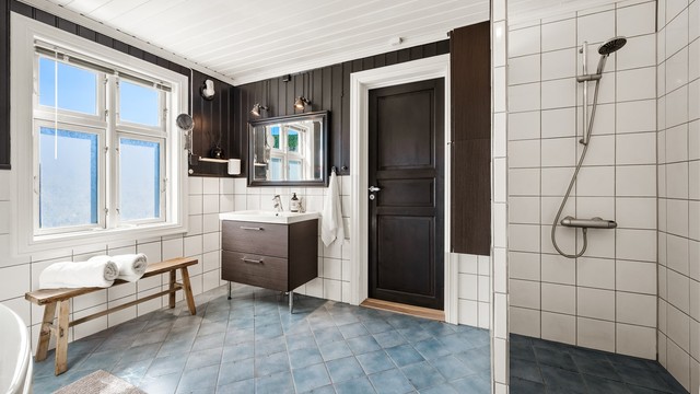 Baderommet er utstyrt med både badekar og dusjnisje med opplegg for dusjforheng.