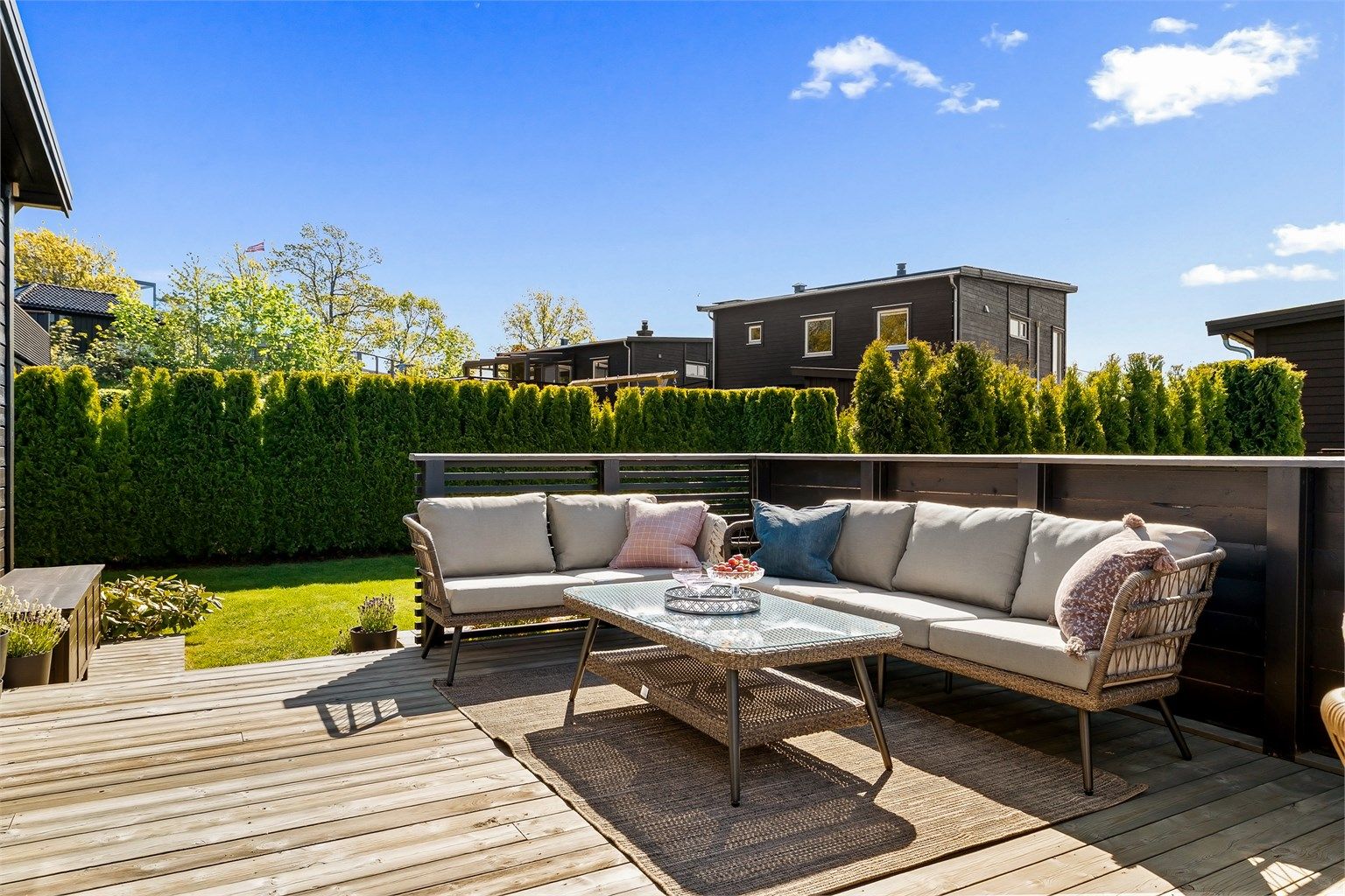 En skjermet og privat uteplass med god plass til både sofagruppe og spisebord.