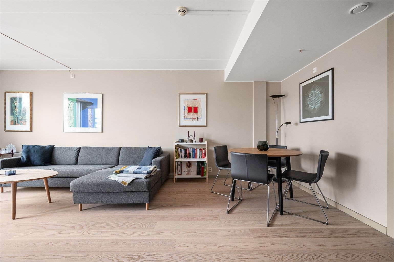 Gjennomgående materialvalg med parkettgulv og malte flater skaper en helhetlig og rolig atmosfære.