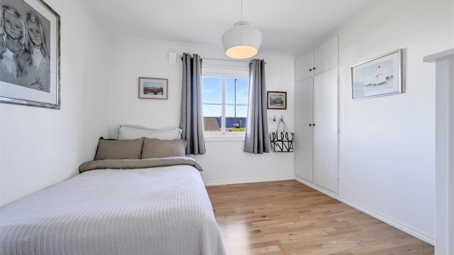 Lyst og trivelig soverom med plass til seng og garderobe.