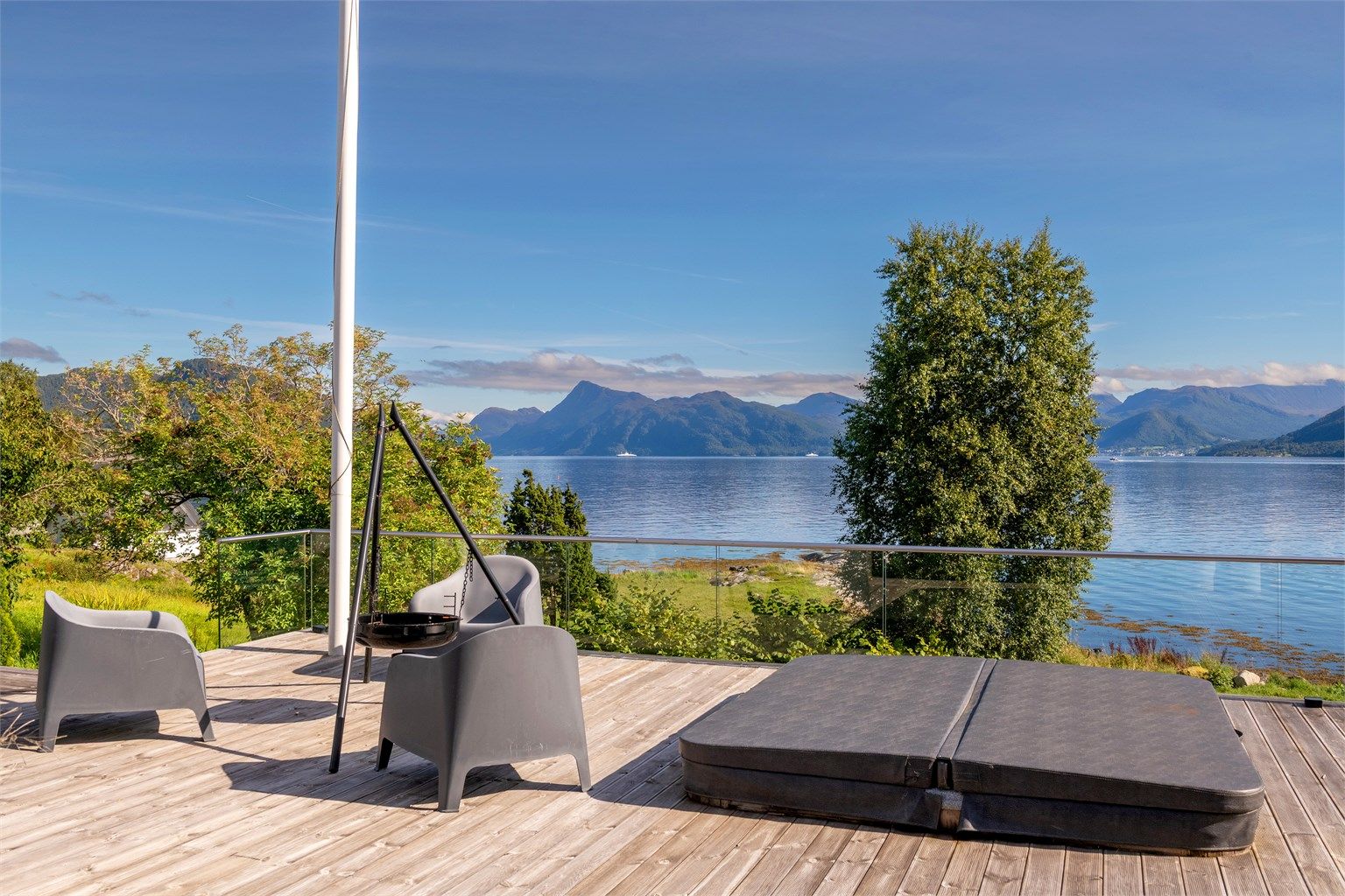Nedfelt jacuzzi på markterrassen med utsikt over fjorden.