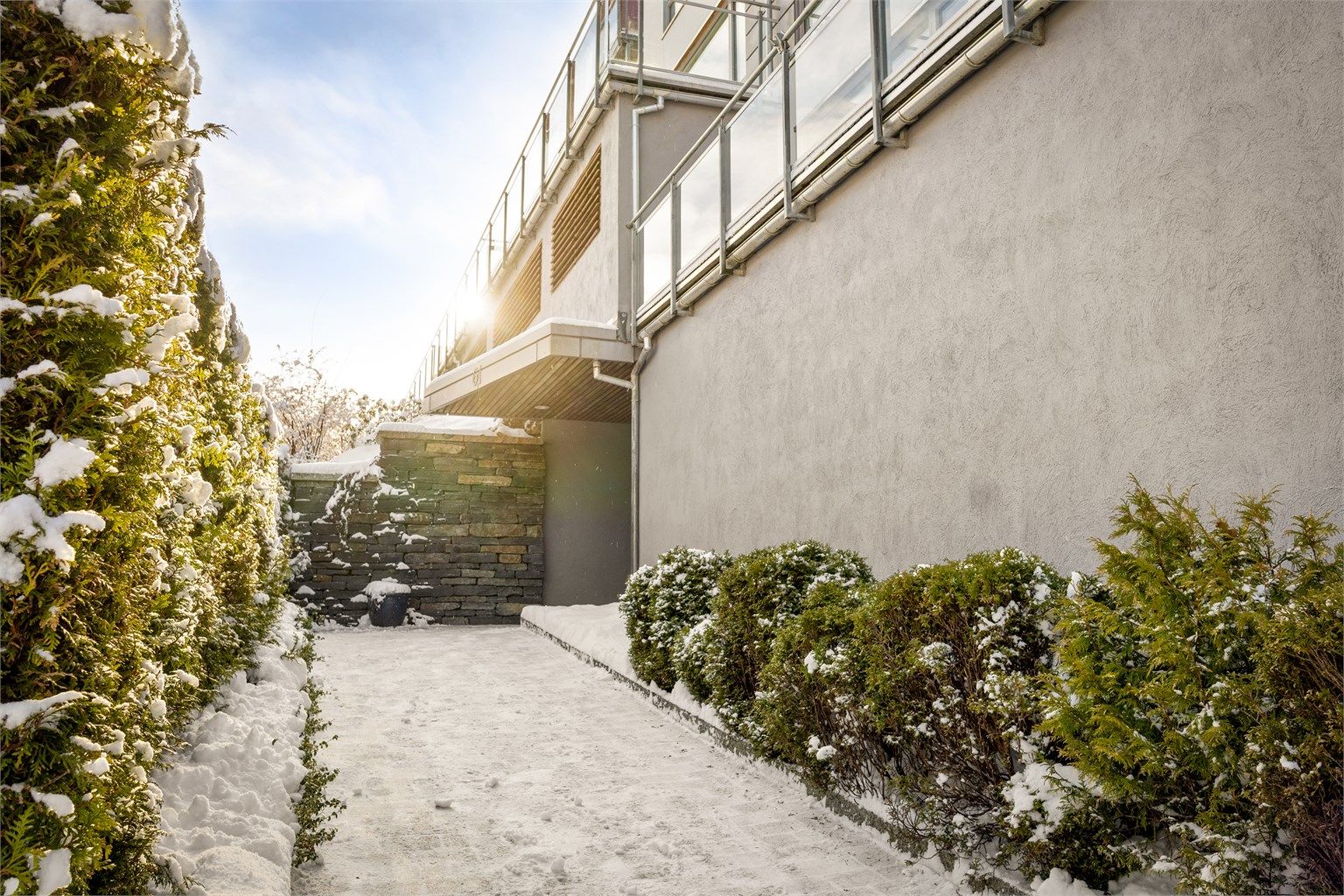 Elegant inngangsparti med fasadestein og grønne omgivelser