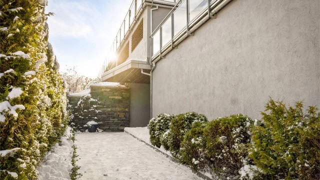 Elegant inngangsparti med fasadestein og grønne omgivelser