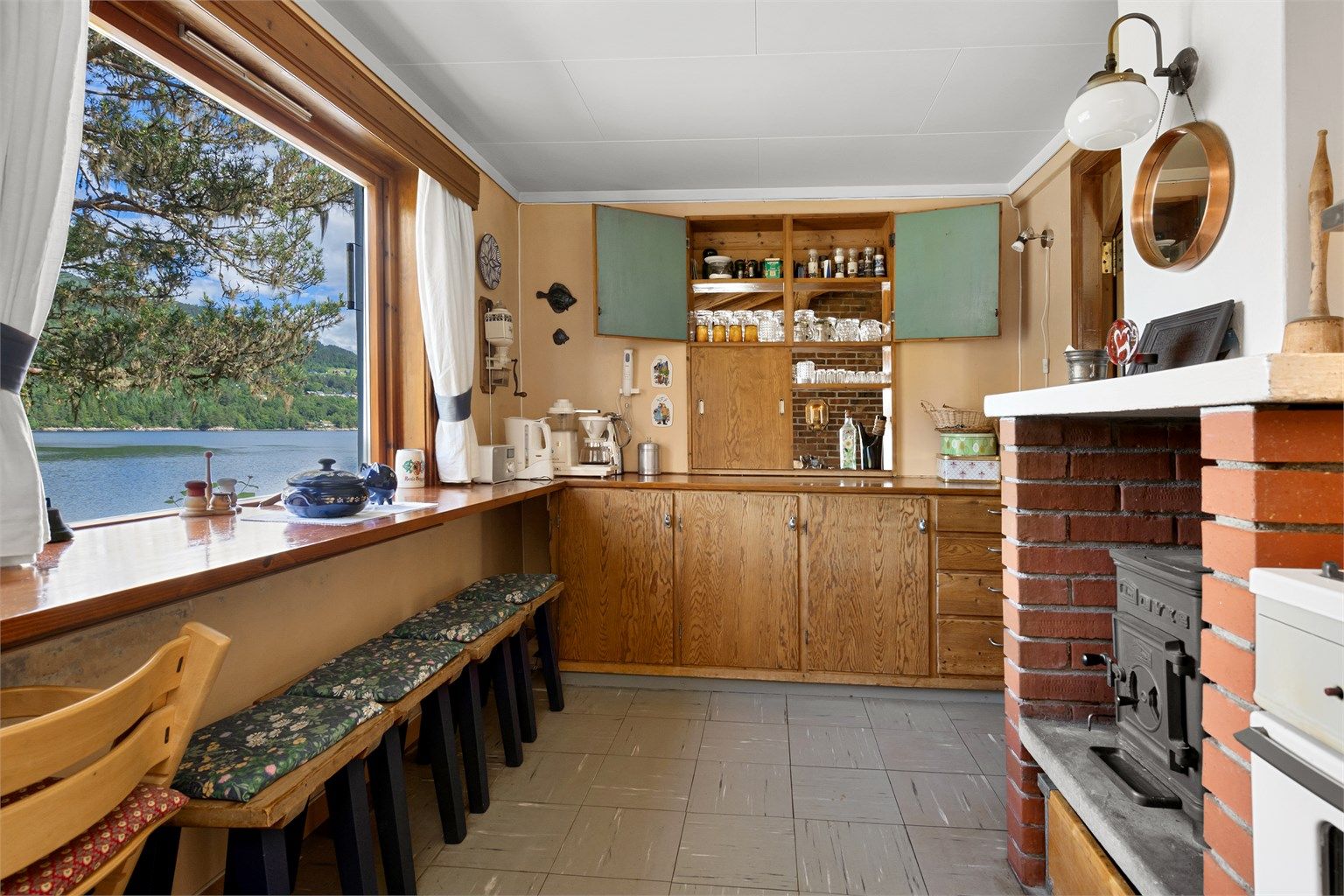 Kjøkken fra byggeår med innredning. Flott utsikt også fra kjøkkenet. Det er vedovn på kjøkkenet.