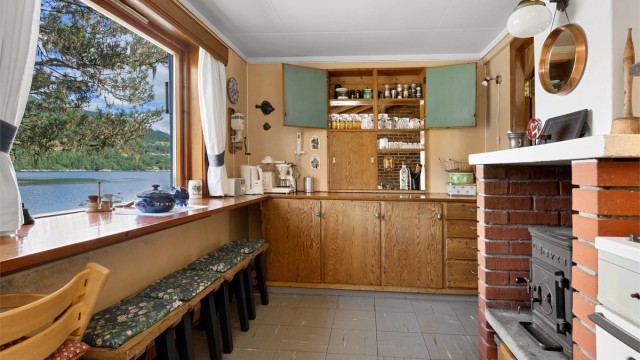 Kjøkken fra byggeår med innredning. Flott utsikt også fra kjøkkenet. Det er vedovn på kjøkkenet.