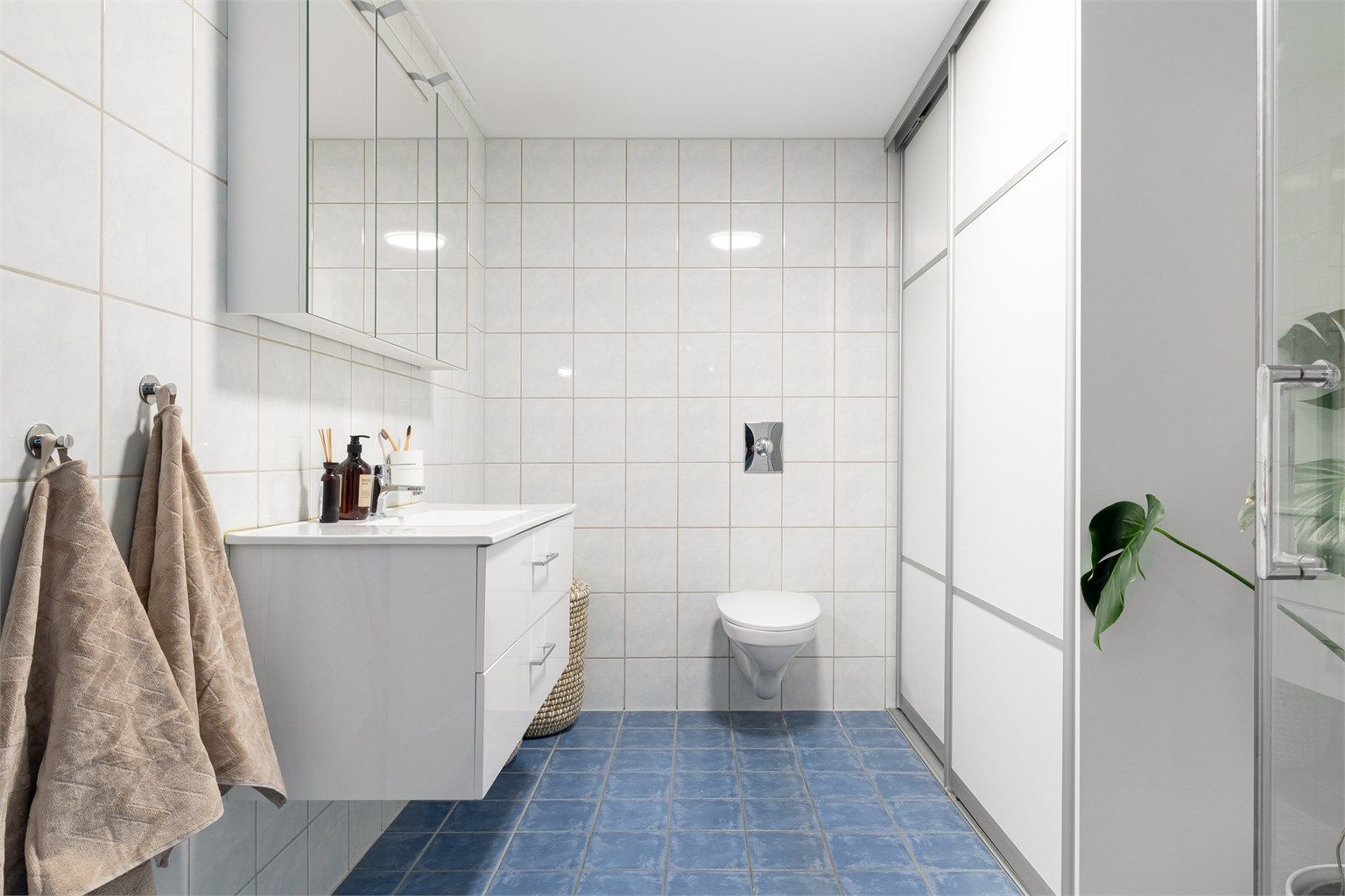 Badet har vegghengt toalett med skyvedører til vask og tørketrommel. Baderomsinnredning fra 2022. 