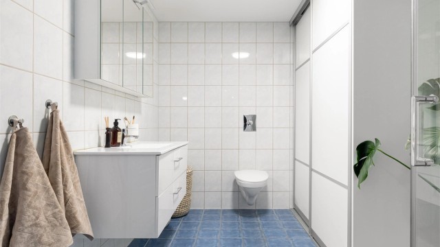 Badet har vegghengt toalett med skyvedører til vask og tørketrommel. Baderomsinnredning fra 2022.