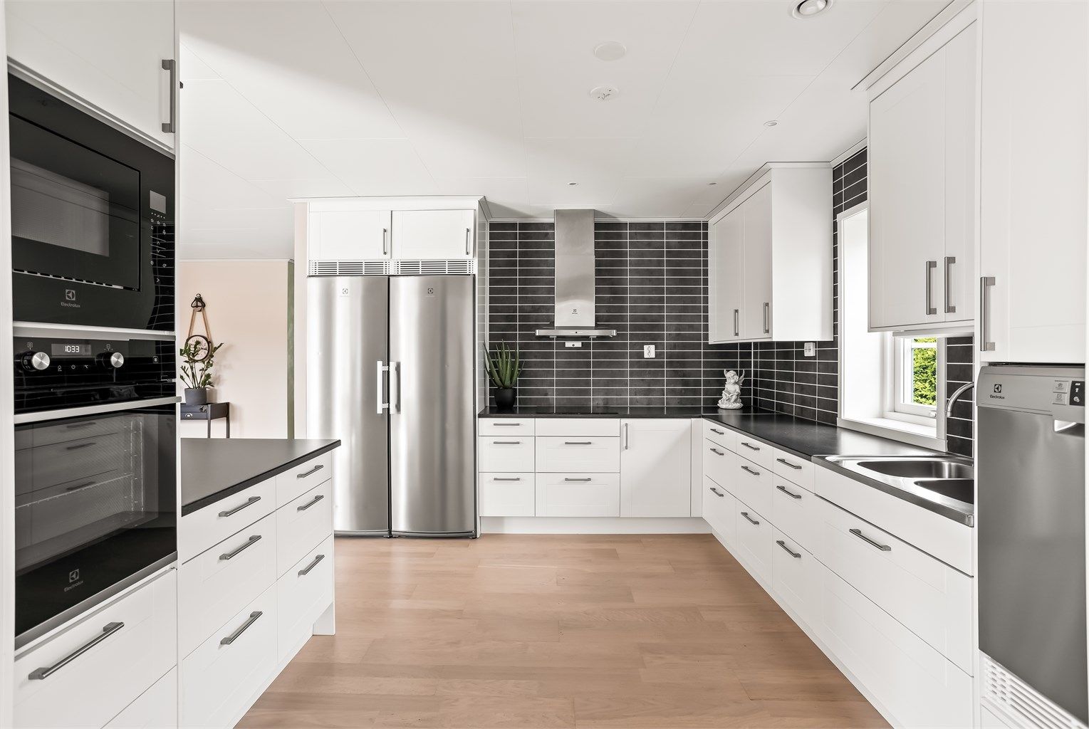 Kjøkken med hvite profilerte fronter, laminert benkeplate og hvitevarer fra Electrolux.