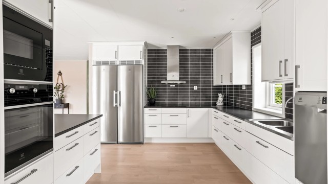 Kjøkken med hvite profilerte fronter, laminert benkeplate og hvitevarer fra Electrolux.