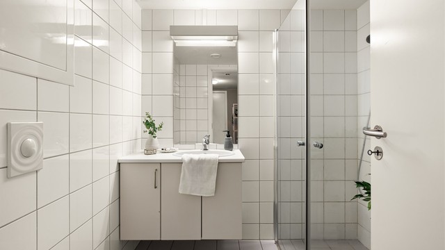 Badet er utstyrt med vegghengt toalett, servant med underskap og dusjhjørne med innfellbare glassdører.