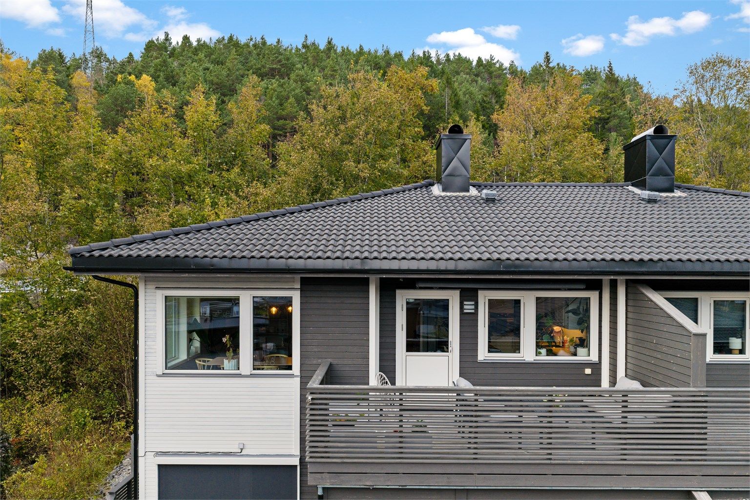 Sørvendt balkong i trekonstruksjon med terrassebord og utgang direkte fra oppholdsrommet.
