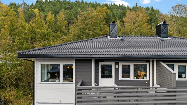 Sørvendt balkong i trekonstruksjon med terrassebord og utgang direkte fra oppholdsrommet.