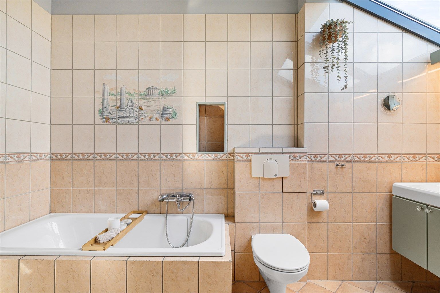 Badet er utstyrt med innmurt badekar, vegghengt toalett og praktisk skittentøyssjakt.