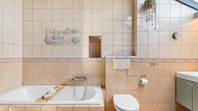 Badet er utstyrt med innmurt badekar, vegghengt toalett og praktisk skittentøyssjakt.