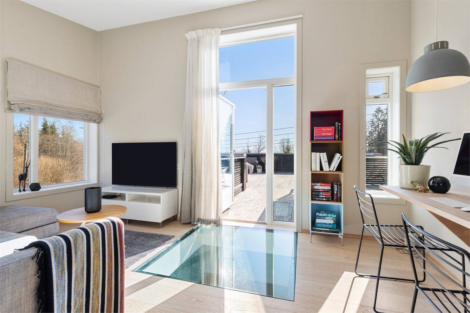 Opp trappen i 2.etasje kommer du først til stuen. Her er det plass til sittegruppe, TV-område og skrivebord/kontorløsning. Stilig detalj med glassgulv ned mot entreen i 1.etasje. Fra stuen er det utgang til en stor takterrasse.