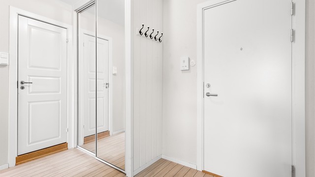 Dørcallinganlegg med åpnerfunksjon og skyvedørsgarderobe med speilfronter i entré.