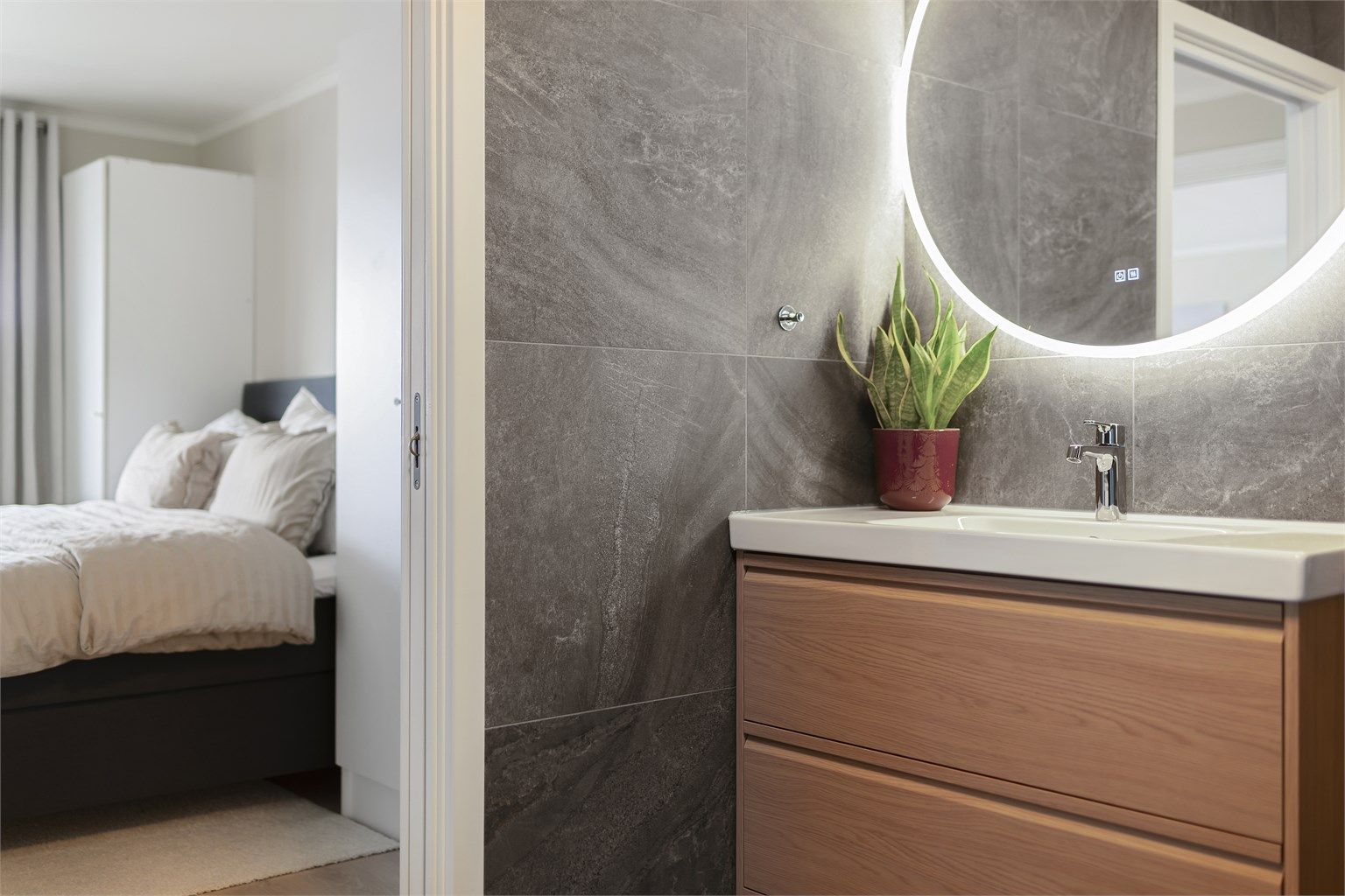 På badet er det en moderne baderomsinnredning og vegghengt speil med integrert belysning og varme