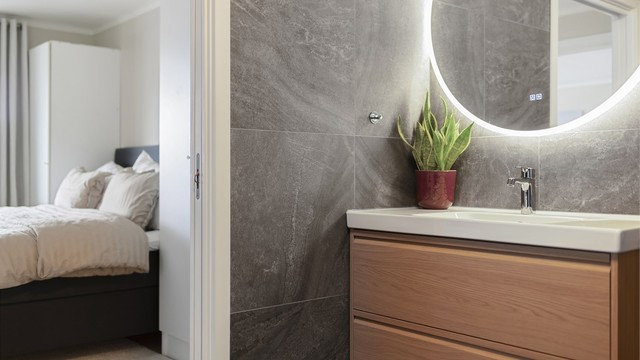 På badet er det en moderne baderomsinnredning og vegghengt speil med integrert belysning og varme