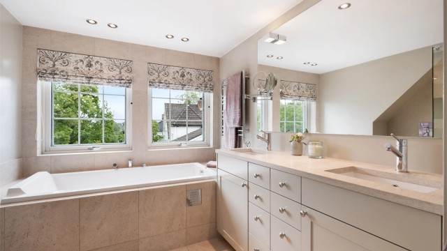 Det er nedsenket himling med downlights. Badet er innredet med frittstående servantskap med to nedsenkede vasker og vegghengt toalett.