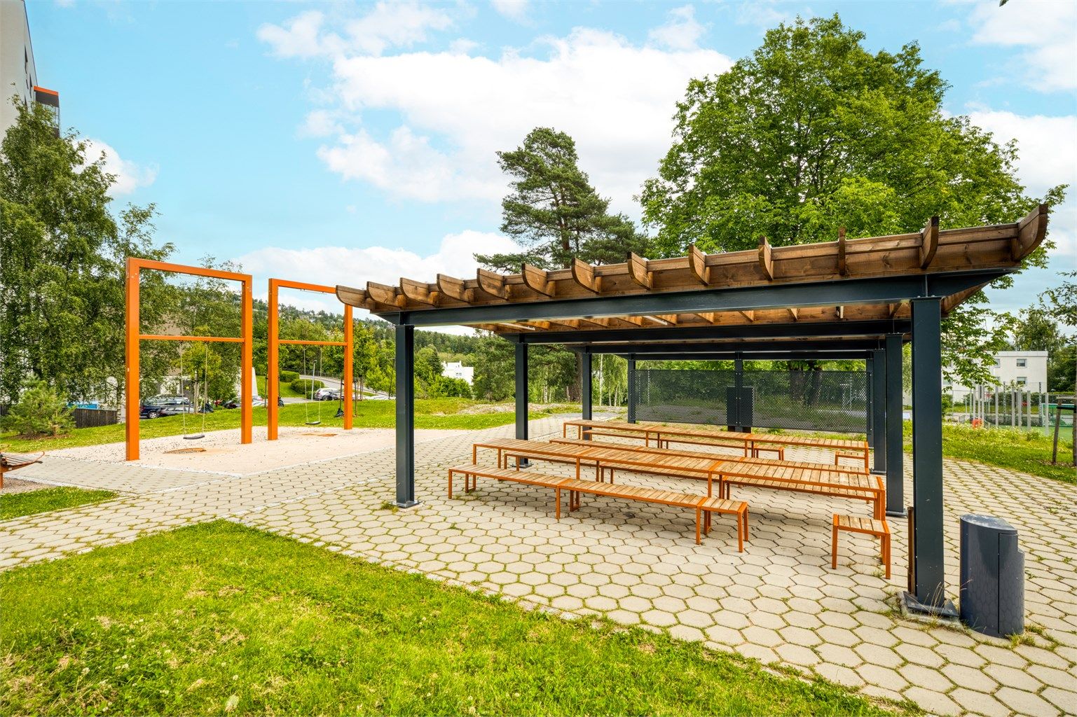 Felles uteområder med pergola, sittebenker og lekeapparater for beboerne.