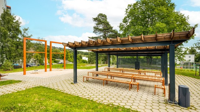 Felles uteområder med pergola, sittebenker og lekeapparater for beboerne.