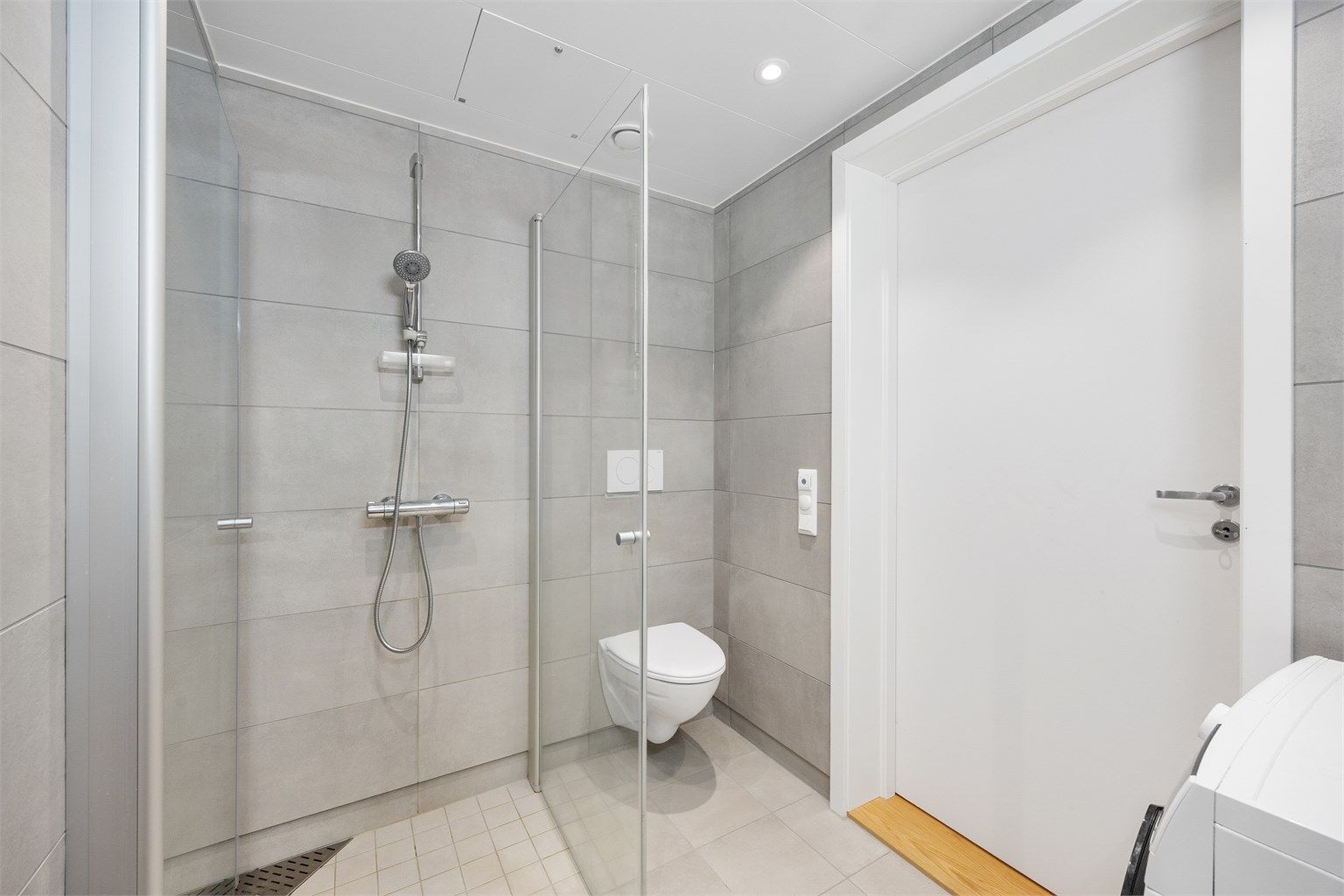 Badet har vegghengt toalett med skjult sisterne og innfellbare glassvegger.