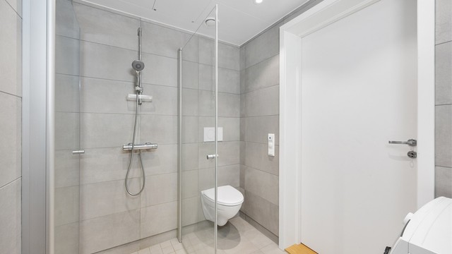Badet har vegghengt toalett med skjult sisterne og innfellbare glassvegger.